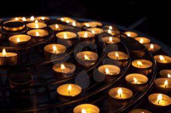Small candles burn in dark interior of Catholic cathedral
