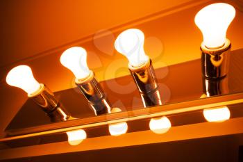 Four shining electrical lamps in a row, modern orange toned illumination 