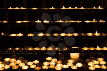 Candles burning on shelves in dark catholic church