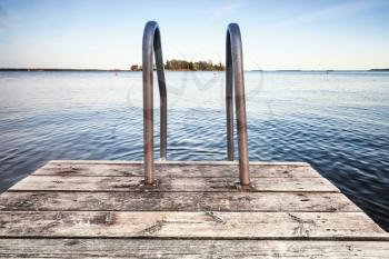 Wooden pier for swimming on still lake coast