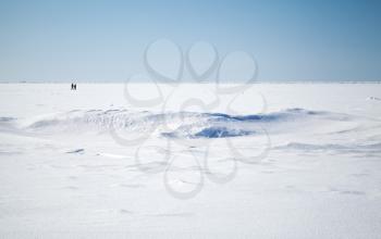 Deep blue sky and snow on frozen Baltic Sea with people walking on ice