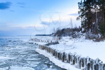 Winter coastal landscape with floating ice and frozen pier. Gulf of Finland, Russia
