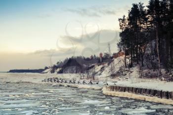 Winter coastal landscape with floating ice and frozen pier. Gulf of Finland, Russia. Vintage toned photo with filter effect