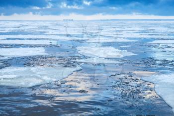 Winter coastal landscape with floating ice fragments on still cold water. Gulf of Finland, Russia