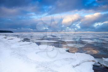 Winter coastal landscape with floating ice on still water. Gulf of Finland, Russia