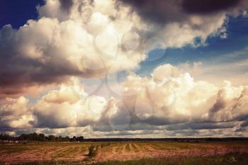 Empty country landscape with dramatic cloudy sky. Vintage toned photo