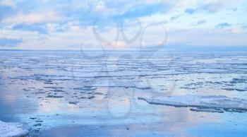 Winter coastal seascape with floating ice fragments on still cold water. Baltic Sea, Gulf of Finland, Russia