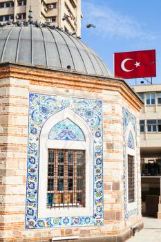 Facade of ancient Camii mosque and Turkish flag banner on the wall. Konak square, Izmir, Turkey