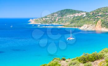 Summer coastal landscape of South Corsica. Pleasure catamaran yacht moored in small azure bay of Piana region, France