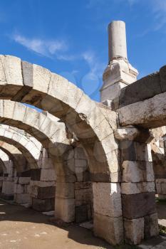 Ancient white broken columns and arches on blue sky background, fragment of ruined roman temple in Smyrna. Izmir, Turkey