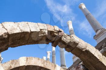 Ancient white columns and arches over blue sky background, fragment of ruined roman temple in Smyrna. Izmir, Turkey