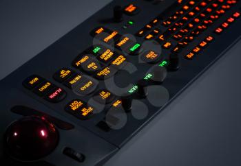 Fragment of colorful illuminated industrial control panel keyboard in the dark. Selective focus
