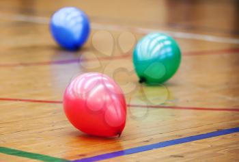 Three colorful balloons on wooden floor of sports hall. Concept of RGB color scheme