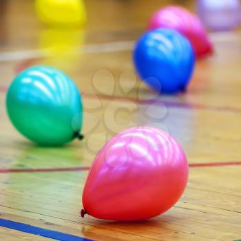 Colorful balloons on wooden floor of sports hall