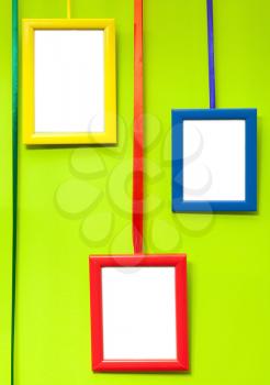 Colorful empty wooden frames on green wall
