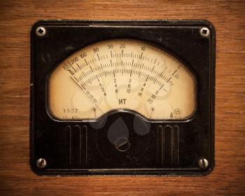 Close-up photo of an vintage electric multimeter on wooden panel