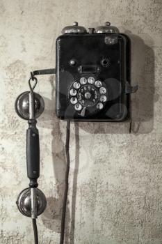 Vintage black phone hanging on old gray concrete wall