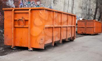 Big metal orange trash containers in the city