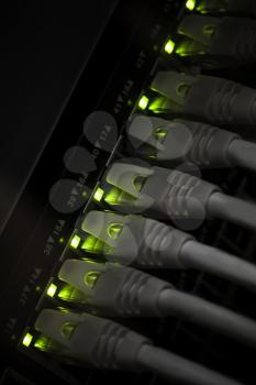 Network hub with green led lights and connected cables. Selective focus