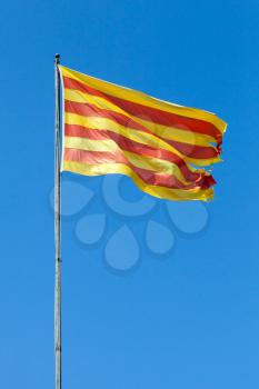 Flag of Catalonia waving on the wind above blue sky