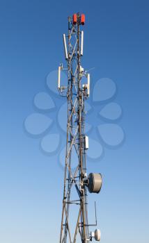 Communication radio tower with devices on blue sky background