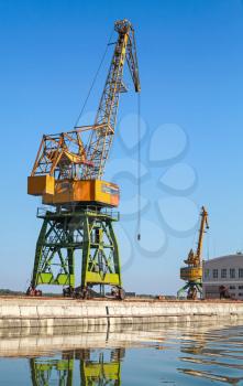 Big industrial harbor cranes works on the river coast in Bulgarian port