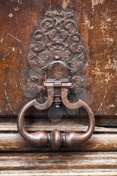 Old rusted knocker on brown wooden door in Paris, France
