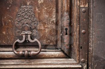 Old rusted knocker on brown wooden door. Paris, France
