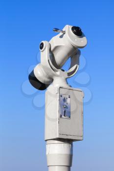 White paid tourist telescope on blue sky background