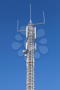 Communication tower with GSM and radio devices above blue sky