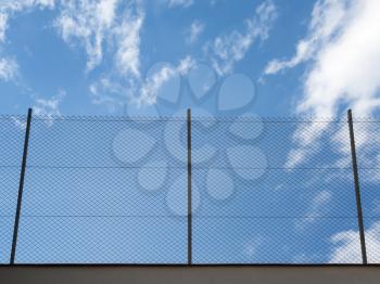 Metal Rabitz mesh fence against blue sky background