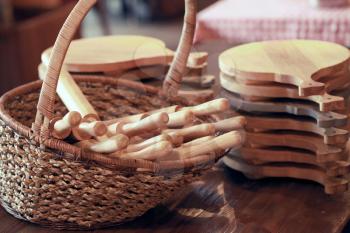 Group of cutting boards and wooden rolling pin in the basket stand on the table. Vintage toned photo filter effect