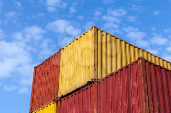Colorful metal Industrial cargo containers are stacked under blue cloudy sky