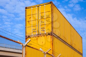 Yellow metal Industrial cargo containers are stacked under blue cloudy sky