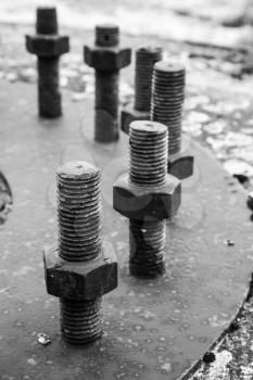 Big black steel bolts and nuts in a circle on rusted industrial cover. Selective focus