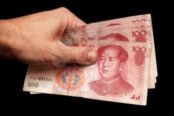 Modern Chinese 100 yuan renminbi banknotes in male hand isolated on black background