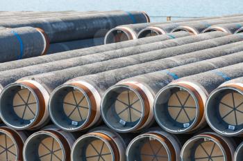 Stacked pipeline tubes lay in outdoor storage area