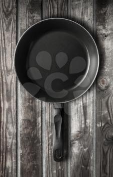 Empty black frying pan stands on old dark gray wooden table background
