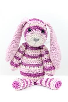 Knitted rabbit toy sitting over white background with soft shadow