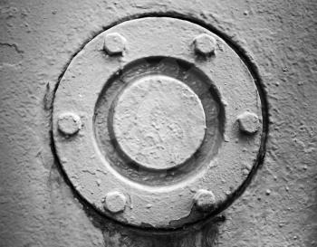 Round gray cover mounted with bolts, abstract old industrial detail