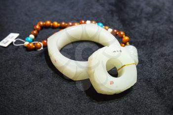 Hangzhou, China - December 2, 2014: Traditional Chinese stone amulet and bracelet made of jade lay on the counter in gemstones shop