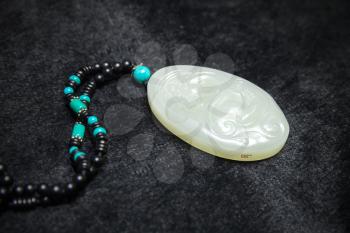 Hangzhou, China - December 2, 2014: Traditional Chinese stone amulet made of jade with dragon art carving lays on black counter in gemstones shop