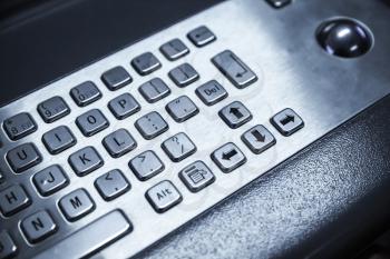 Industrial keyboard made of steel with trackball. Blue toned photo, selective focus with shallow DOF