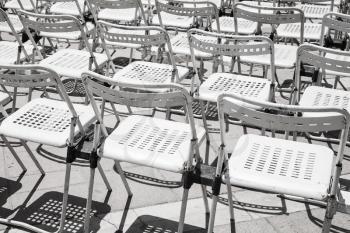 Rows of empty white metal chairs in an open-air concert hall
