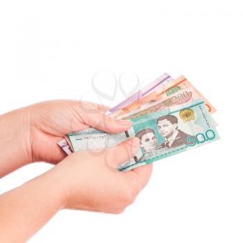 Dominican Republic banknotes in female hand, closeup studio photo isolated on white background