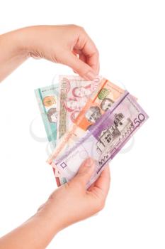 Dominican Republic money in female hands, close up studio photo isolated on white background