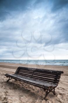 Old empty wooden bench stands on sandy beach, Mediterranean sea coast, Spain