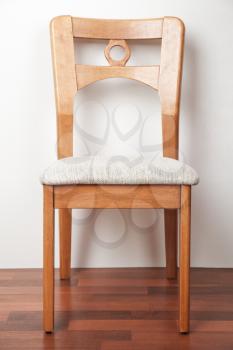 Wooden chair against a white wall, closeup vertical photo