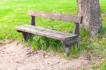 Old wooden bench on roadside in summer park 