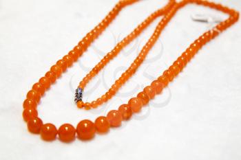 Chinese necklace made of red round agate stones lays on white counter